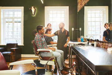 Male barbers and customers in barbershop