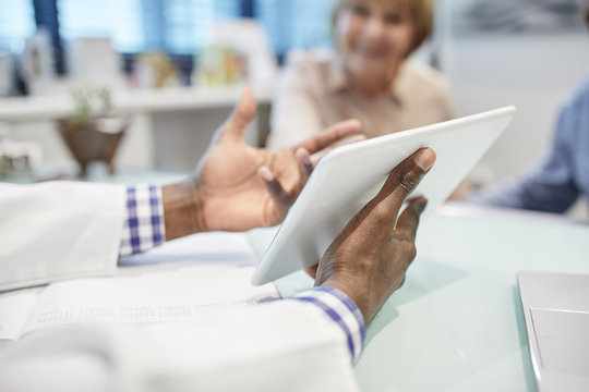 Doctor with digital tablet talking with patient in doctors office
