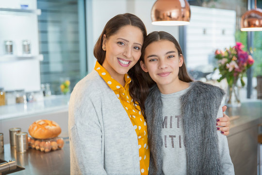 Portrait happy mother and daughter hugging in kitchen