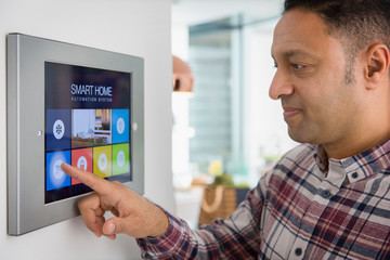 Man setting smart home navigation system alarm at touch screen