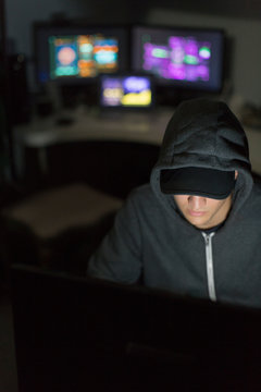 Hacker in hoody at computer in dark room