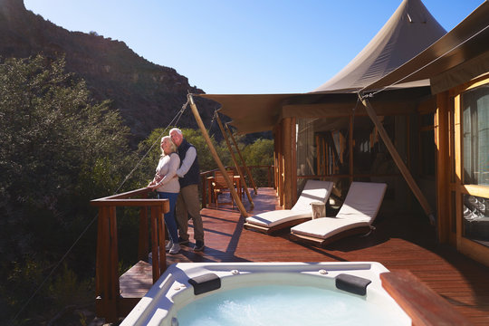 Affectionate senior couple on sunny luxury safari lodge balcony
