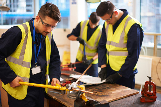 Male students using equipment in shop class workshop