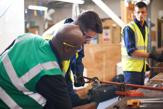 Male instructor helping students in shop class workshop