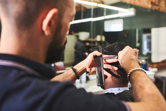 Male barber giving customer a haircut in barbershop