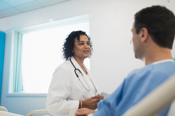 Doctor making rounds, talking with patient in hospital room
