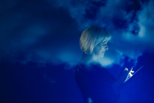Double exposure businesswoman with digital tablet against blue sky with clouds