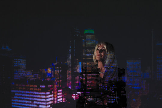 Double exposure thoughtful businesswoman against highrise lights at night