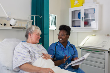 Female nurse talking with senior patient in hospital room