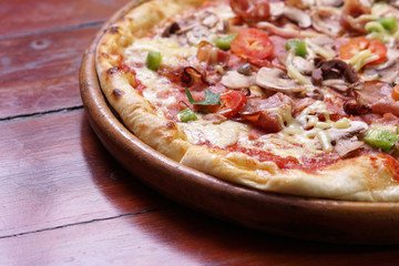 Whole pizza with prosciutto and bacon on wooden background