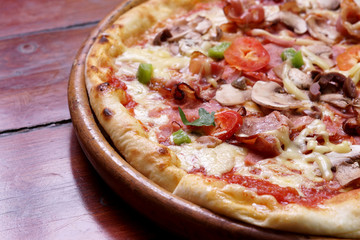 Whole pizza with prosciutto and bacon on wooden background