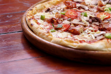 Whole pizza with prosciutto and bacon on wooden background