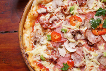 Whole pizza with prosciutto and bacon on wooden background