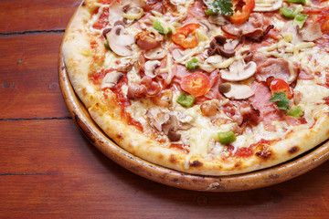 Whole pizza with prosciutto and bacon on wooden background