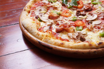 Whole pizza with prosciutto and bacon on wooden background