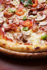 Whole pizza with prosciutto and bacon on wooden background