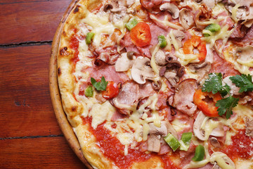 Whole pizza with prosciutto and bacon on wooden background