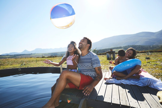 Playful family with beach ball at sunny, summer swimming pool - Powered by Adobe