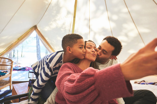 Happy, affectionate family taking selfie in camping yurt