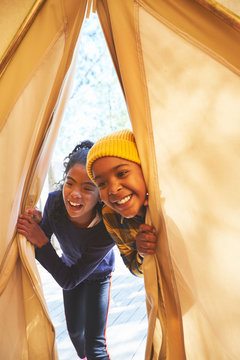 Playful brother and sister peeking into camping teepee