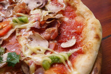 Whole pizza with prosciutto and bacon on wooden background