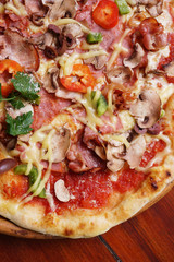 Whole pizza with prosciutto and bacon on wooden background