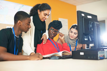 Multi-ethnic college students studying at computer in computer lab