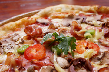 Whole pizza with prosciutto and bacon on wooden background