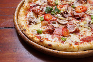Whole pizza with prosciutto and bacon on wooden background