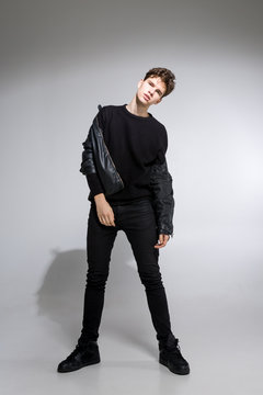 full length portrait of young fit man in dark cloths on the white background. Young Male Fashion Model Posing In Casual Outfit. Attractive young fashion model wearing black in leather jacket