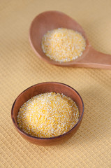 Clay Cup and wooden spoon with corn grits on the table, top view