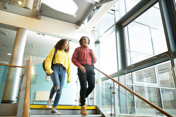 Smiling college students descending staircase