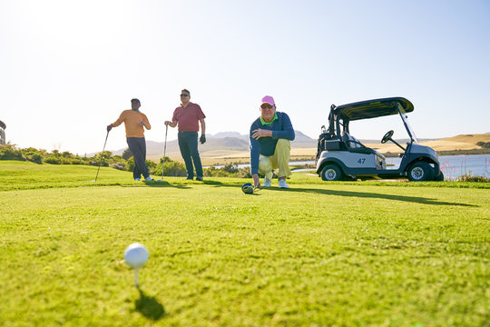 Male golfers preparing to tee off at sunny tee box