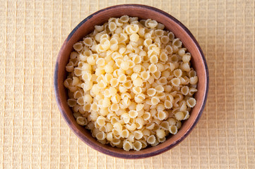 Pasta in a clay bowl on the table, top view