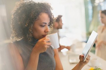 Businesswoman drinking coffee and using digital tablet