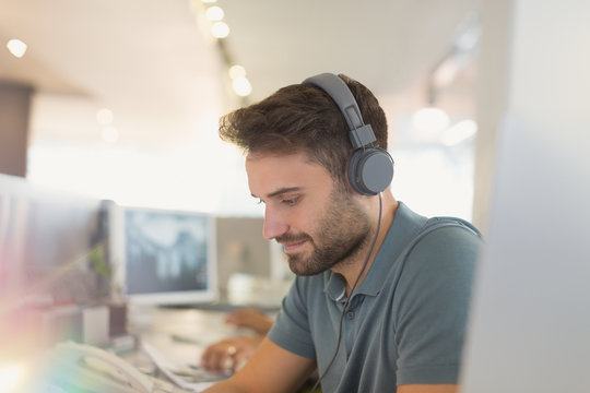 Creative businessman with headphones working in office
