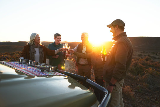 Safari tour group toasting champagne glasses on sunset - Powered by Adobe