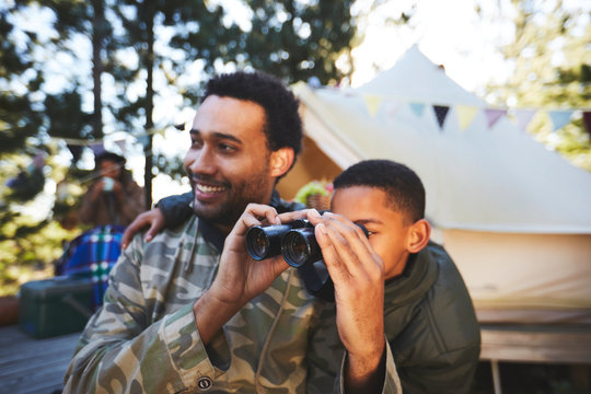 Curious father and son with binoculars at campsite