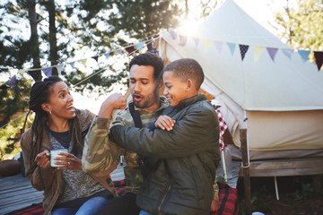 Playful father flexing biceps muscles for son at campsite
