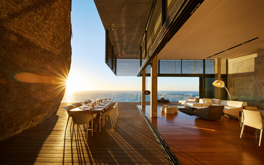 Sun setting behind modern luxury patio dining table with ocean view