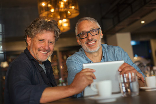 Portrait smiling men using digital tablet and drinking coffee at restaurant table