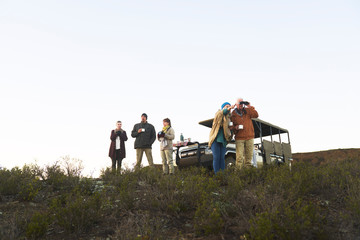 Safari tour group drinking tea and using binoculars on hill