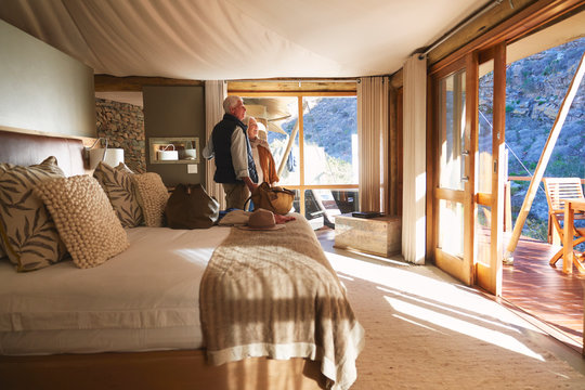Happy senior couple arriving in sunny safari lodge hotel room