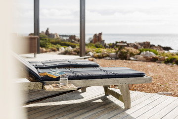 Book and water at lounge chair on patio overlooking ocean
