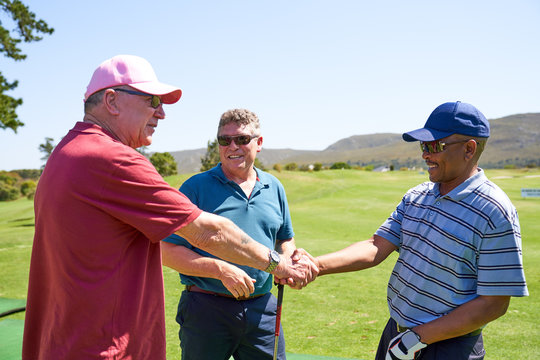 Male golfers shaking hands on sunny golf course - Powered by Adobe