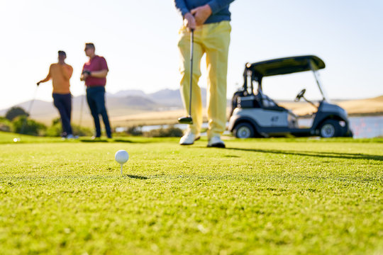 Male golfer preparing to tee off on sunny golf course - Powered by Adobe