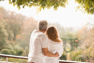 Affectionate couple hugging looking at autumn trees on patio