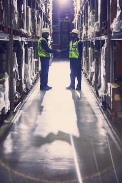 Workers handshaking in aisle of distribution warehouse