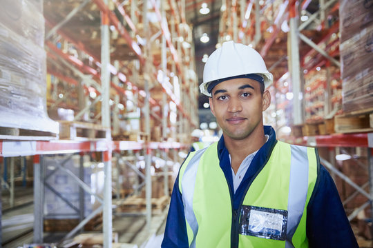 Portrait confident worker in hard-hat in distribution warehouse aisle