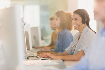 Smiling businesswoman with headset working at computer in office